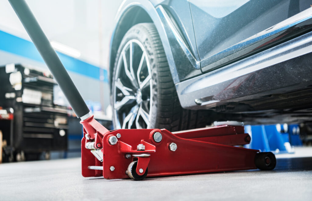Modern Vehicle and the Floor Jack Lift Vehicle Servicing and Maintenance Inside Auto Service Center.