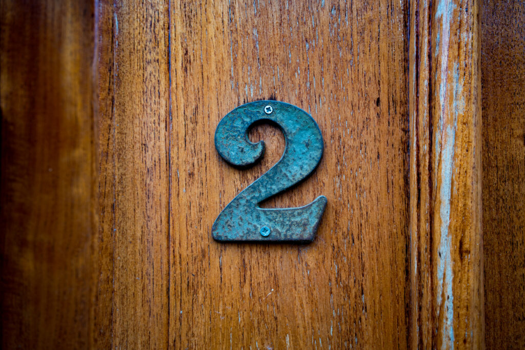 Bronze house number two (2) on a wooden door