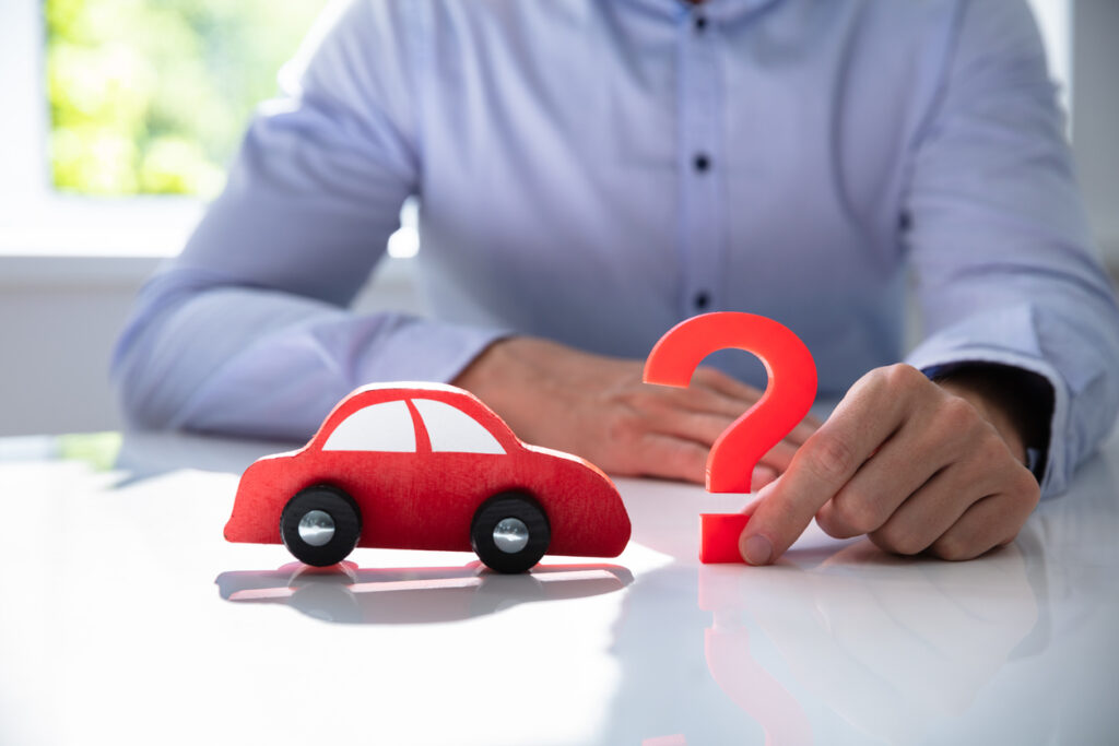 Person Hand Holding Question Mark Next To Car Model