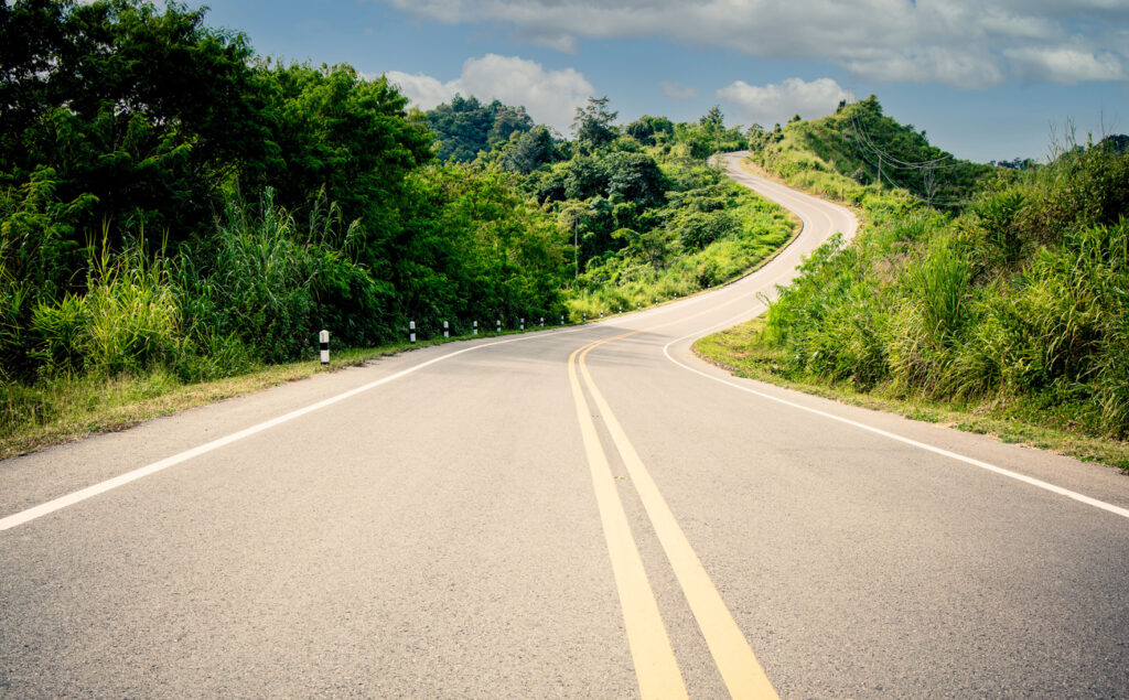 The  curve of the road trough  with green forest with the  nature landscape background
