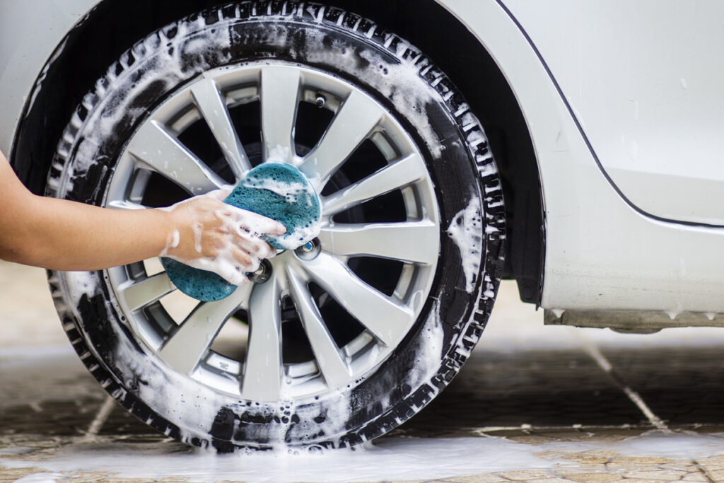 This image is a picture of wiping the car with a blue microfiber cloth by hands.Car wash concept.