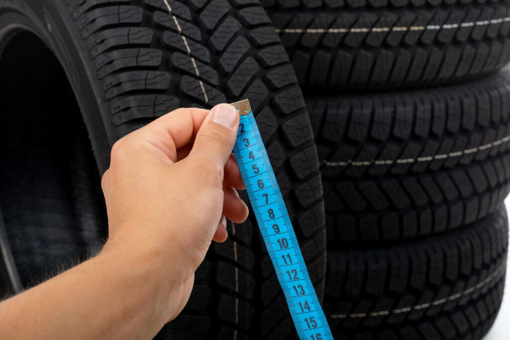 Close up picture of black new car tyre and mechanic's hand next to
