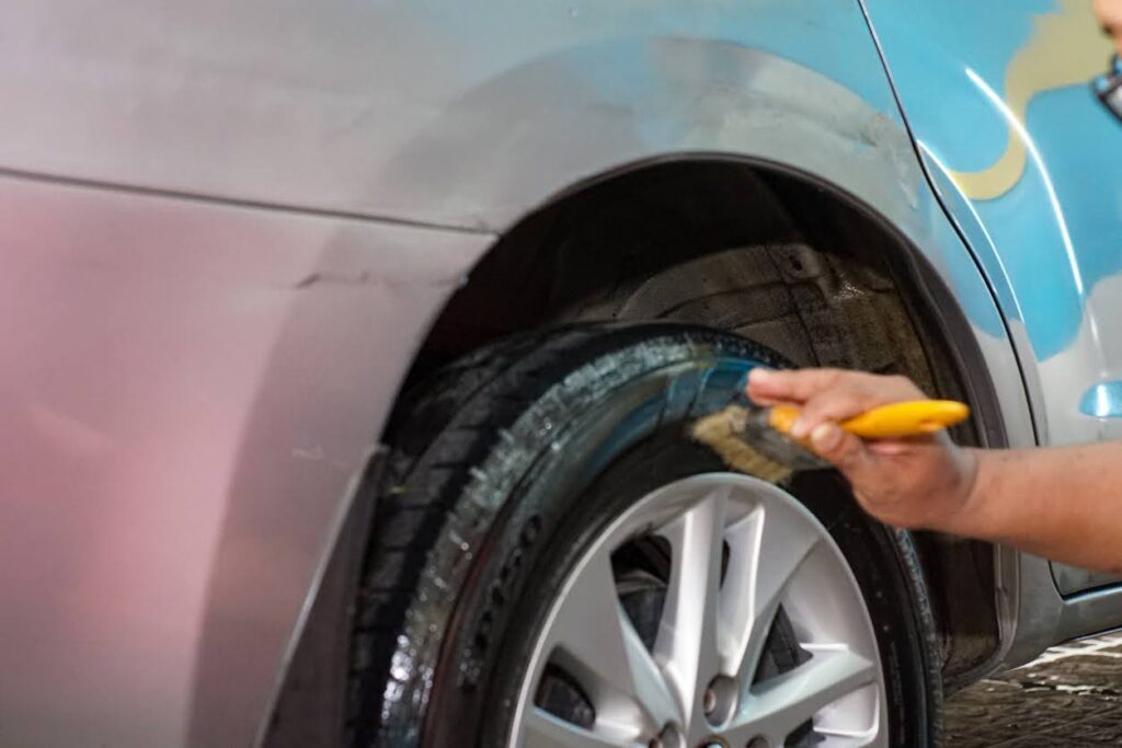 worker cleaning car rim