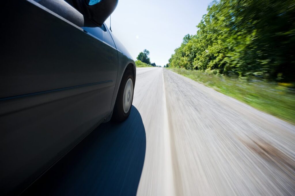 Side shot of a car speeding on a rural road.