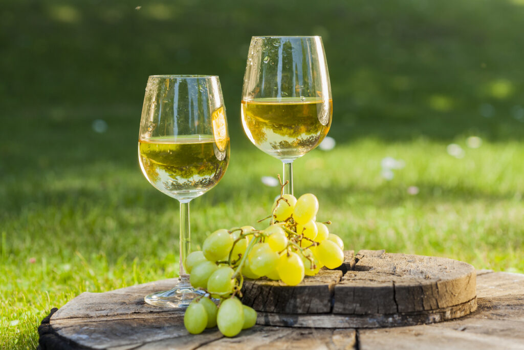 white wine with grapes on old wooden table